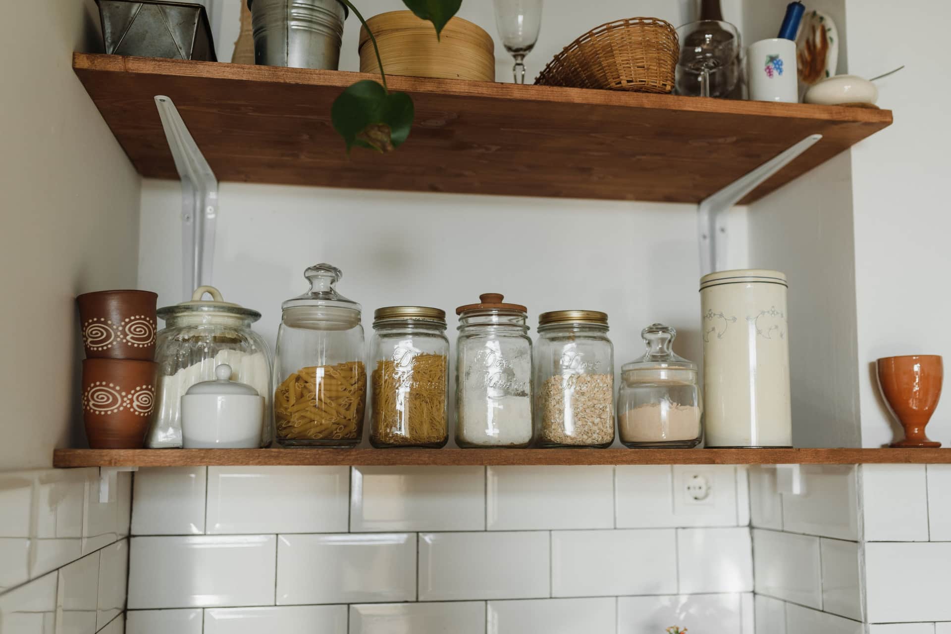 Empty glass jars standing in a row on a wooden kitchen shelf
