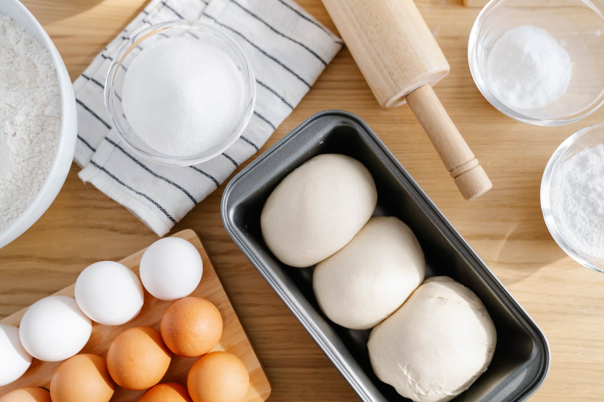 Bread-making tools laid out on a wooden surface: a jar, a scraper and a cloth